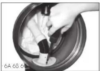 Close-up of hands using a tool to clean or brush the substance in a circular container (no visible text or symbols)
