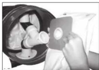 Person using a handheld device to clean or inspect a circular component, no visible text or symbols