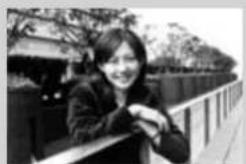 Black-and-white photo of a smiling woman leaning on a balcony with trees and a fence in the background (no visible text or symbols)