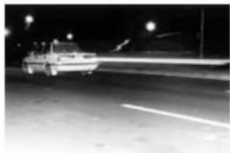 Night street scene with a car driving on a road, light trails visible (no text or symbols)