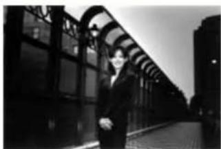 Black-and-white photo of a person standing beside a curved glass archway at night (no visible text or symbols)