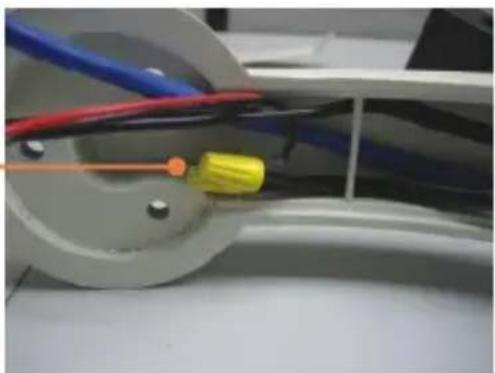 Close-up of a mechanical component with wires and a yellow tool, no visible text or symbols