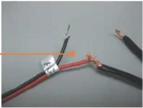 Close-up of two black and red wires with exposed copper wires, no text or symbols visible