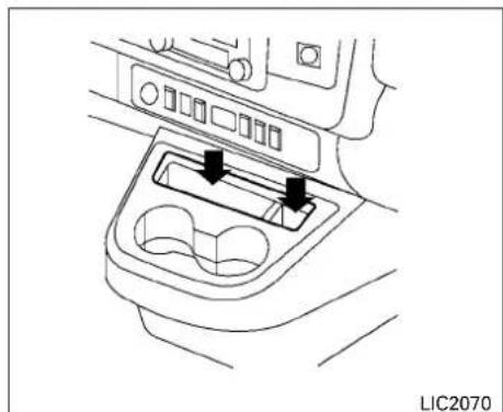 Line drawing of a car interior with two directional arrows pointing to a central component (no text or symbols)