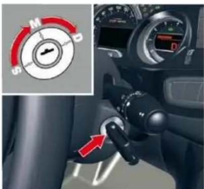 Car dashboard control panel with directional dial indicator and red arrow pointing to a mode switch