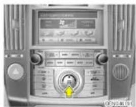 Control panel of a car with digital display and rotary dial, showing Chinese text and a yellow arrow indicating the dial's center.