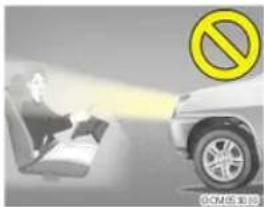 Safety warning image showing a person using a device to emit a car, with a yellow prohibition symbol nearby.