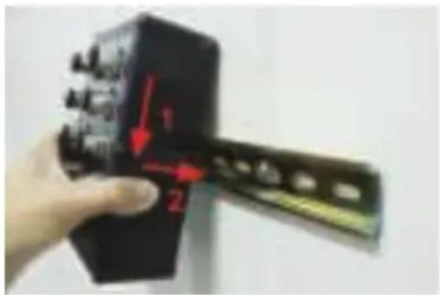 Hand holding a black electronic component with red arrows and numbered labels 1 and 2 indicating measurement or assembly steps.
