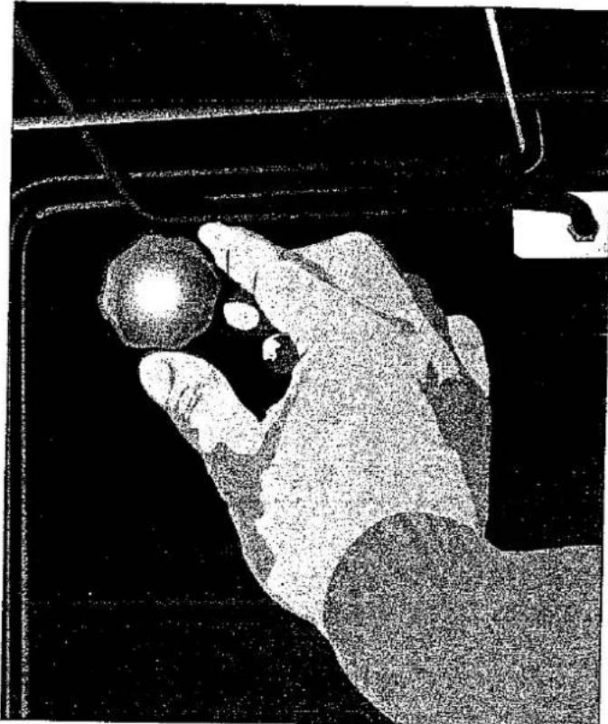 Schwarz-Weiß-Foto einer Person, die ein Werkzeug verwendet, um mit einem kugelförmigen Objekt in einem Fahrzeug zu interagieren (kein sichtbarer Text oder Symbole)