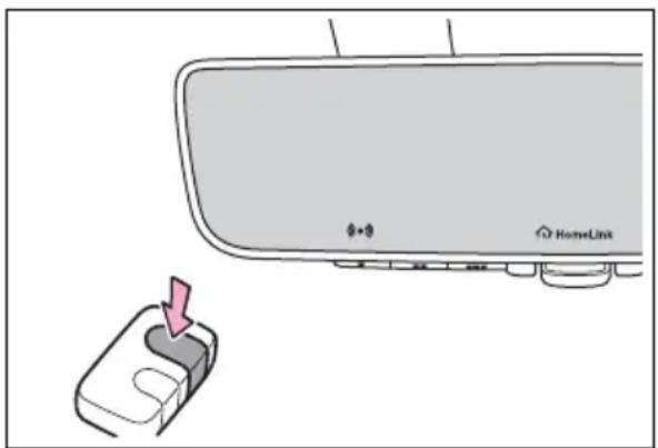 Diagram showing a car rearview mirror with HomeLink logo and a small inset device labeled 'HomeLink' pointing to the front panel.