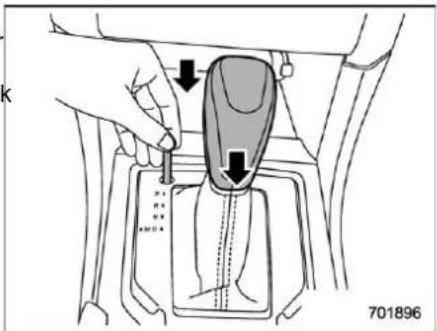 Diagram showing a hand pressing a component into a car gear shift, with arrows indicating motion or force direction.
