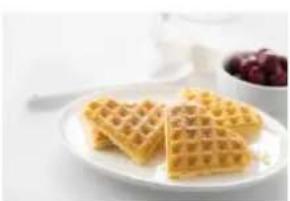 Plate of golden waffles with a bowl of red cherries in the background (no text or symbols visible)
