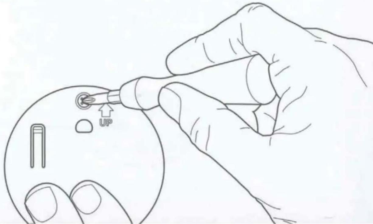 Diagram showing a hand using a pen to apply an upward arrow on a circular component, with labeled parts and directional arrows.