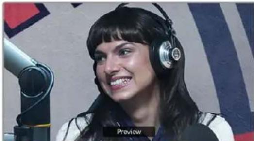Woman wearing headphones and singing into a microphone (no visible text or symbols)