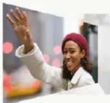 Woman in white coat and red hat waving, blurred background with bokeh lights (no text or symbols visible)