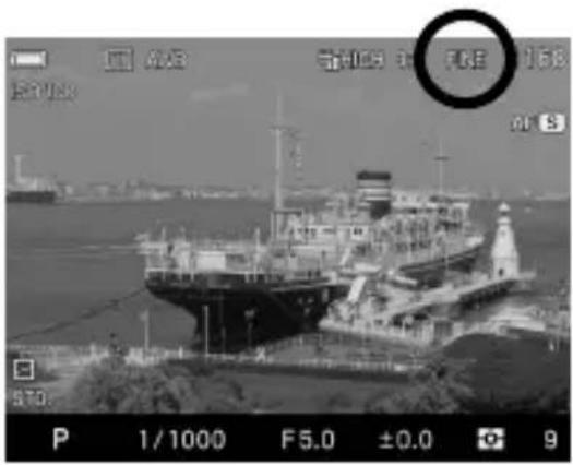 Black-and-white photo of a large cargo ship docked at a port, with camera settings and frame numbers visible in the corner.
