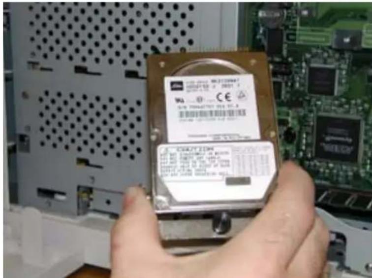 Close-up of a hand holding an electronic device with visible model number and certification marks, placed on a computer motherboard.