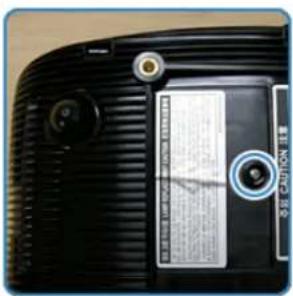 Close-up of a hand inserting a label on a device, with a blue arrow pointing to the label and text.