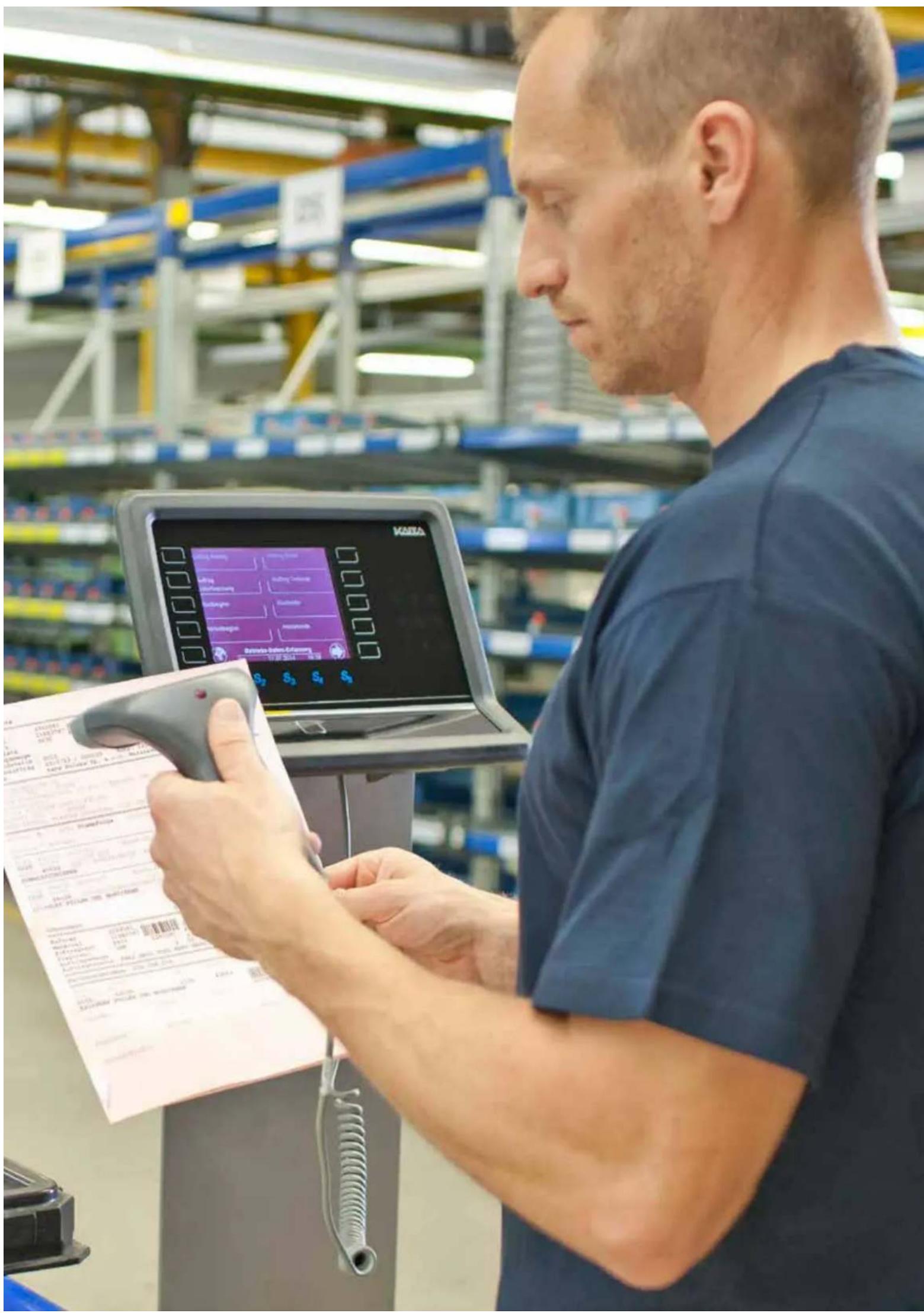 Factory worker scanning a product page with a digital touchscreen display showing manufacturing process steps