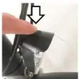 Close-up of a finger pressing down on a mechanical component with a downward arrow indicator (no text or symbols visible)