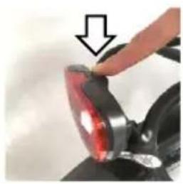 Close-up of a hand holding a red-lit mechanical component with an arrow pointing to it (no text or symbols visible)