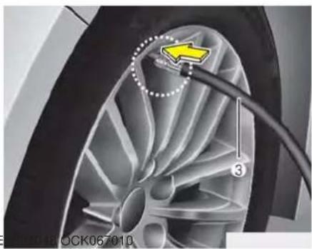 Close-up of a car wheel with a yellow arrow pointing to a specific component, connected by wires (no text or symbols visible)