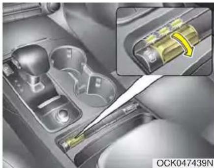Interior view of a car gear shift lever with a close-up inset showing a yellow bandage on the shaft (no text or symbols visible)