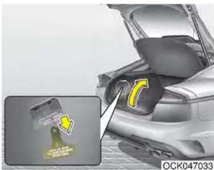 Close-up of a car trunk with a yellow arrow indicating a component being inserted, showing no text or symbols on the main subject.