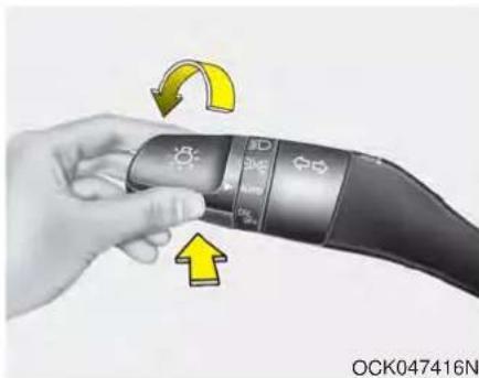 Hand holding a handheld device with circular buttons and a yellow arrow indicating rotation (no text or symbols on the device itself)