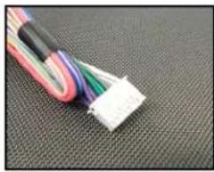 Close-up of a colorful cable with white connector on a textured black surface (no text or symbols visible)