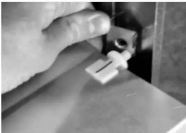 Close-up of a hand holding a white plastic object, possibly a tool or component, with no visible text or symbols.