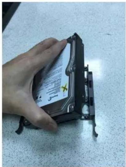 Hand holding a hard disk drive with visible label and warning symbol on the cover