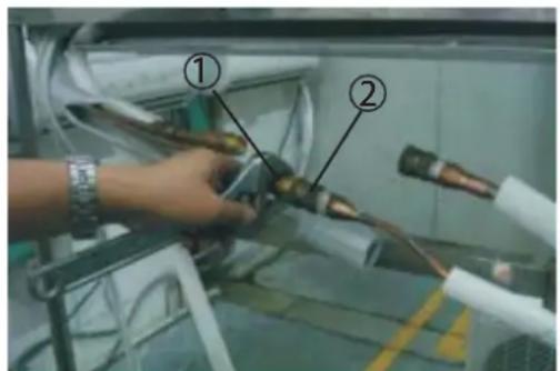 Photo of a hand holding two connected pipes labeled ① and ②, likely indicating inspection or testing steps.