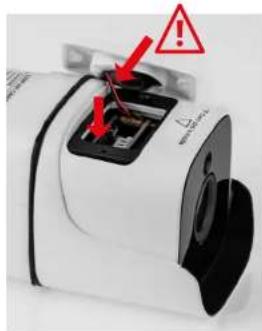 Close-up of a white electronic device with black components and red warning symbols (no readable text or labels)