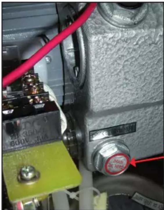 Close-up of industrial control panel with visible text labels and a red arrow pointing to a component