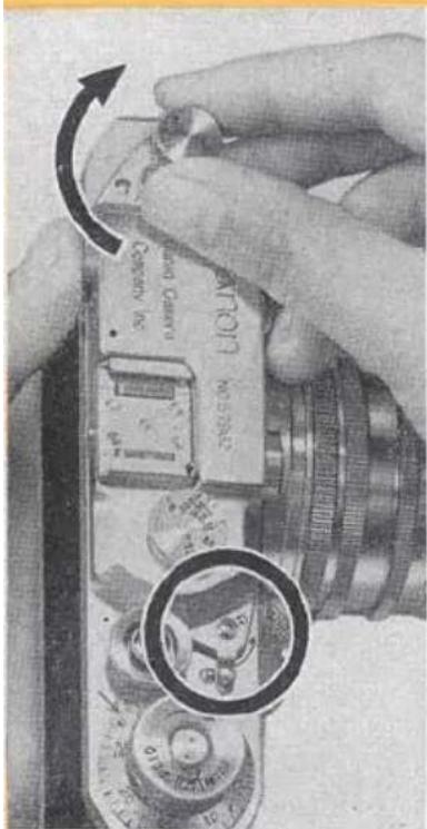 Close-up of hands holding a vintage camera module with visible serial number and lens, showing a magnified inset of the lens's lens.