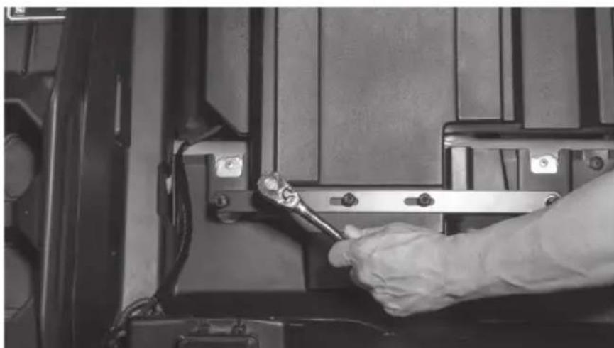 Close-up of a gloved hand using a wrench to adjust or install a mechanical component (no visible text or symbols)