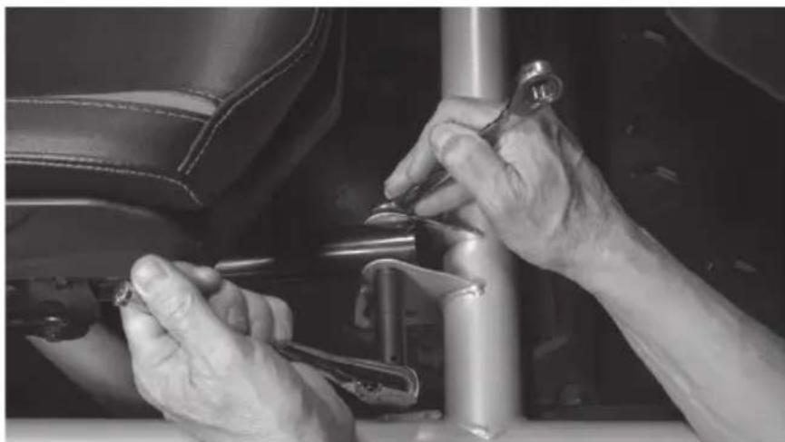 Close-up of hands using a wrench to adjust or install a mechanical component on a vehicle (no visible text or symbols)