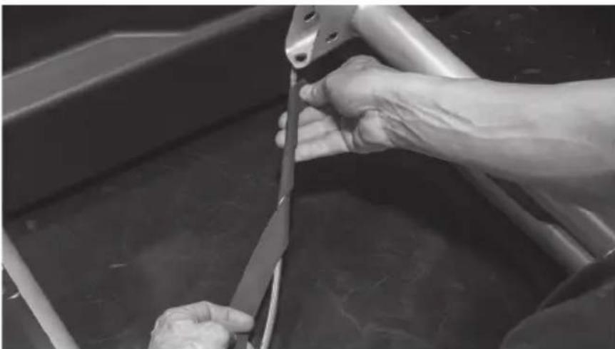 Close-up of hands using a tool to cut or repair material in a metal basin (no visible text or symbols)
