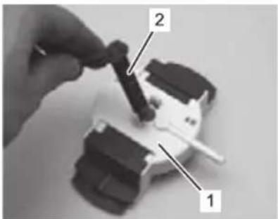 Close-up of a hand holding a small black object with labeled parts 1 and 2