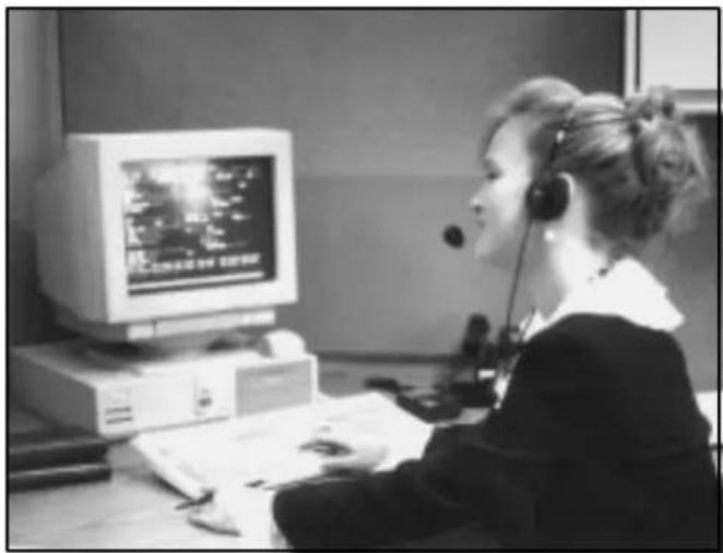 Black-and-white photo of a person in a headset working at a computer, with no visible text or symbols on the device or background.