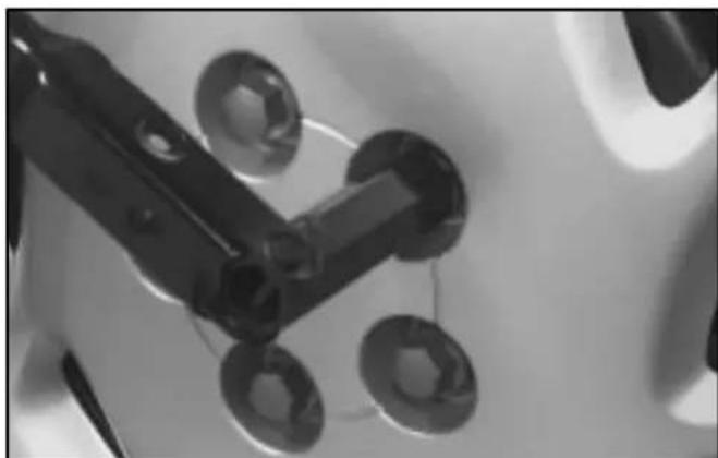 Close-up of mechanical components with circular holes and a black tool handle (no visible text or symbols)