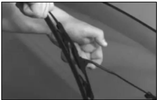Close-up of hands holding a black object with wires, possibly a bow or rod (no visible text or symbols)