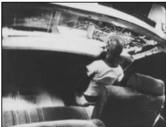 Black-and-white photo of a child sitting on a bench in front of a large vehicle, no visible text or symbols