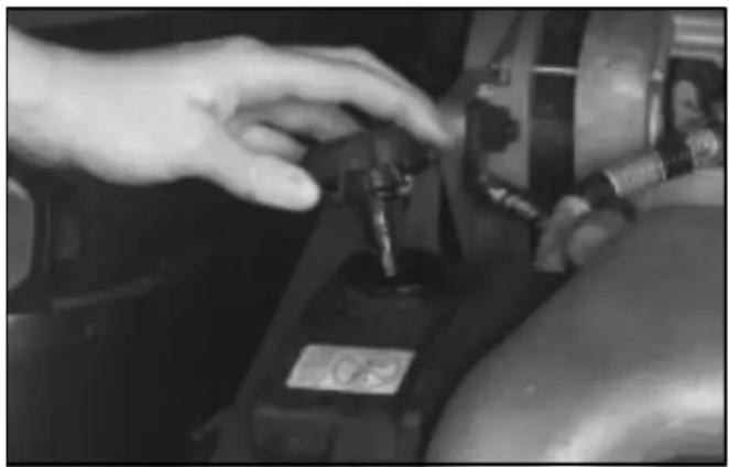 Close-up of a hand adjusting a mechanical component with a label (no visible text or symbols)