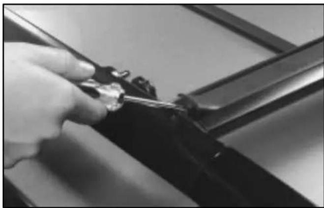 Close-up of a hand using a tool to adjust or install a dark mechanical component (no visible text or symbols)