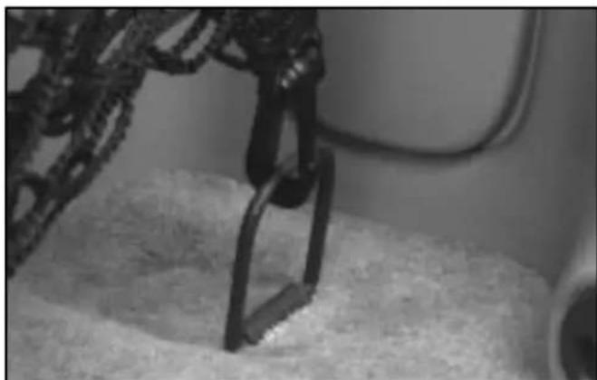 Close-up of a robotic arm interacting with a textured surface (no visible text or symbols)