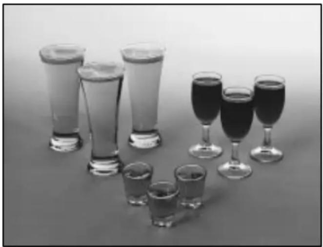 Black-and-white photo of various glasses and wine glasses arranged on a plain surface (no text or symbols visible)
