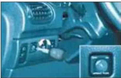 Close-up of a car dashboard with a hand operating the control panel and an inset showing a circular dial (no visible text or symbols)