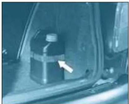 Interior view of a car showing a fuel can and a bottle inside the hood (no visible text or symbols)